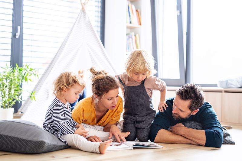 Photo of Small Family laying on floor reading a book