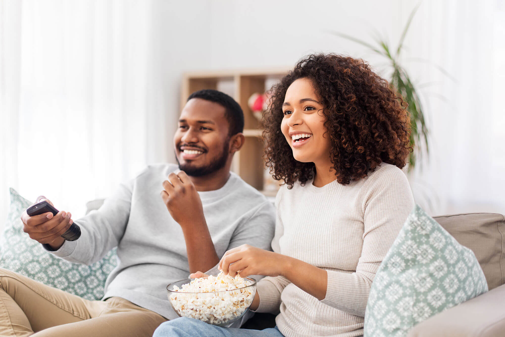Photo of Man and Woman sitting on Couch with Bowl of Popcorn