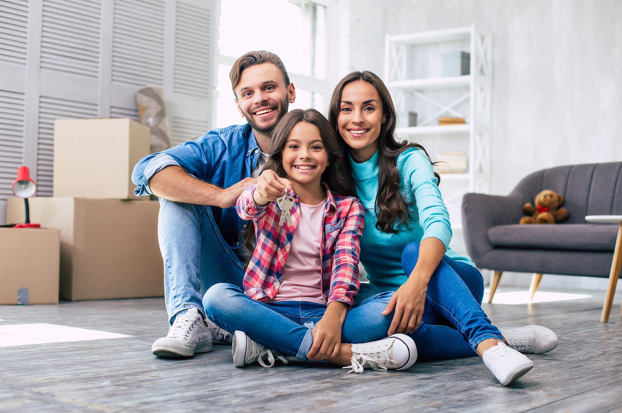 Photo of a Small Family sitting in front of Boxes holding Keys